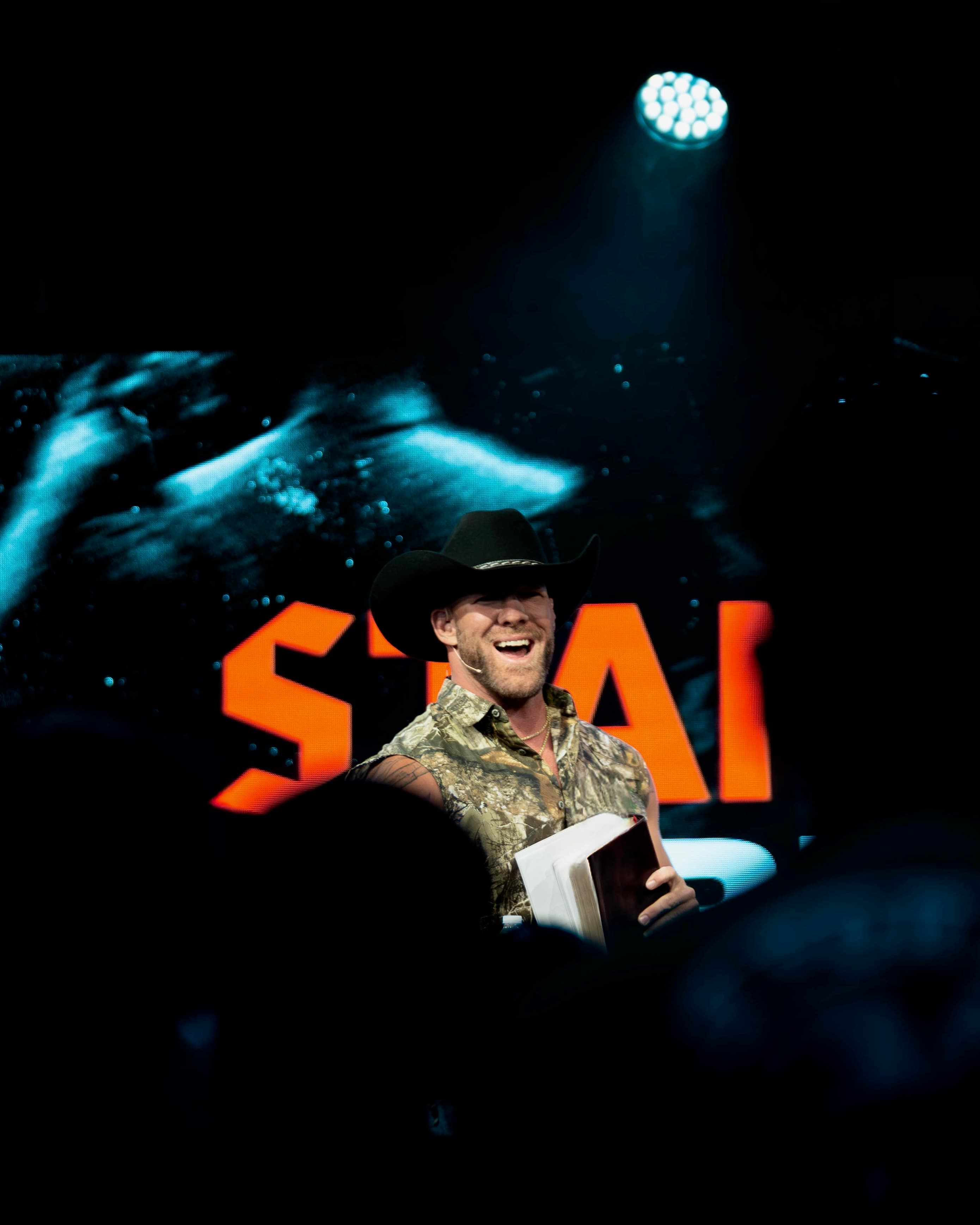 Mike laughing with open Bible on stage at Eleven22 Stand Firm